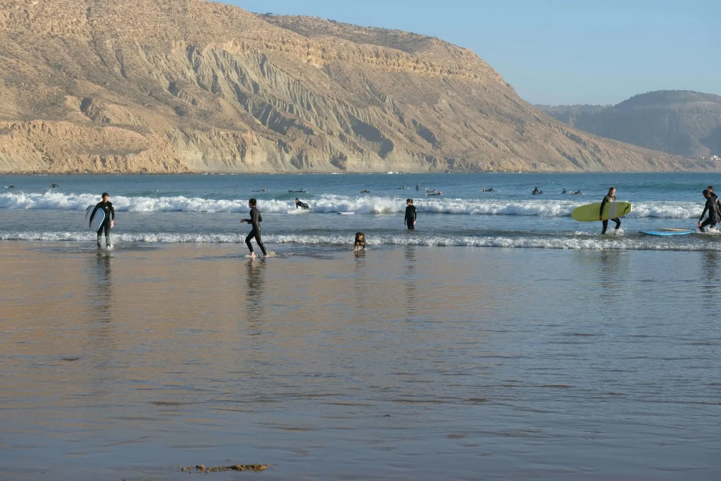 Surfing in Morocco for Beginners: A Local’s Ultimate Guide a group of beginners surfing in Morocco with mountains in background