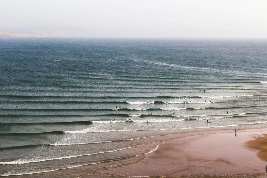 Surfing in Morocco for Beginners: A Local’s Ultimate Guide a group of people surfing on imsouane beach with long waves